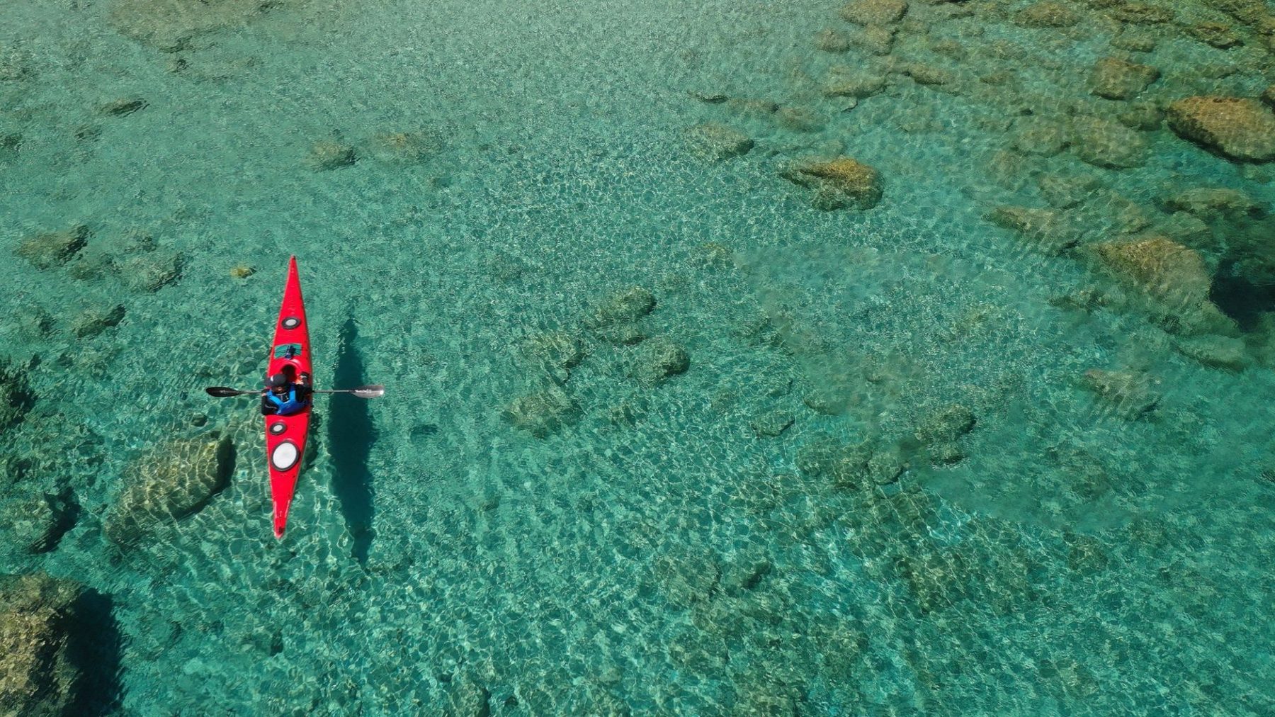 Aerial view of a tropical island with crystal-clear lagoon waters, showing the scale of a resort's location